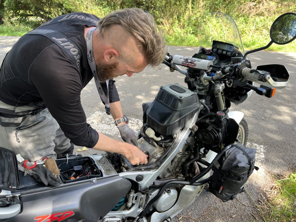 Wiggy fixes motorcycle by road side.